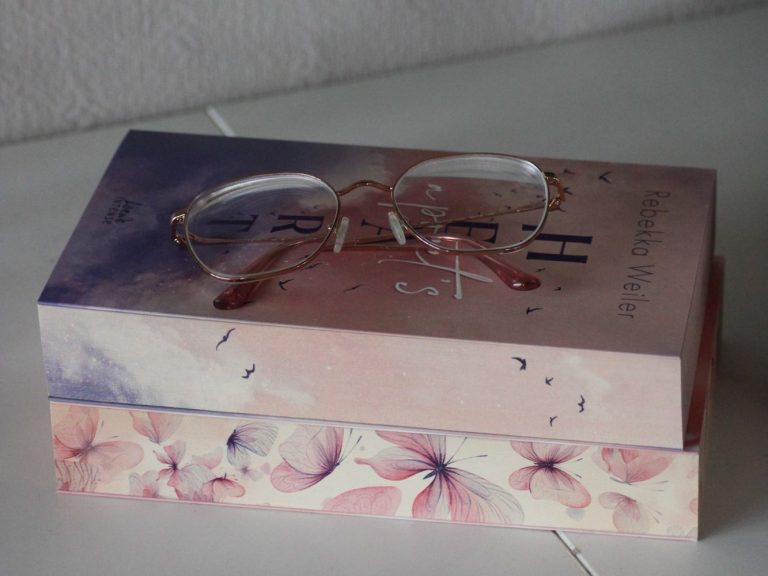 Ein Buch mit einer Brille darauf, dekoriert mit floralen Mustern.