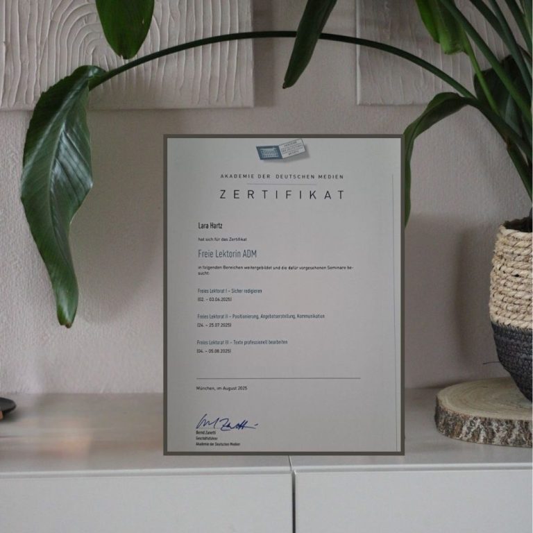 Zertifikat in einem Rahmen, platziert vor einer Pflanze und einem dekorativen Behälter.